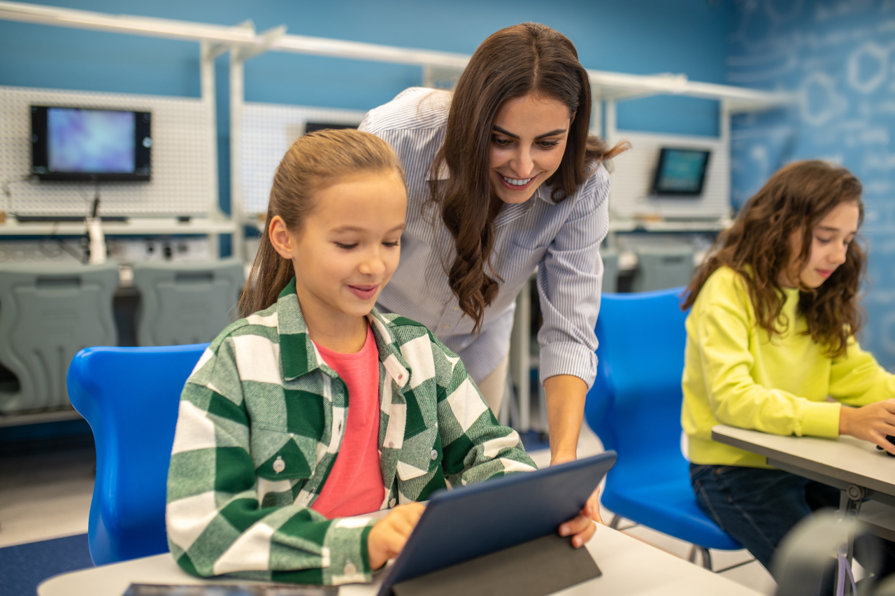 Teacher guiding a student one-on-one on a tablet